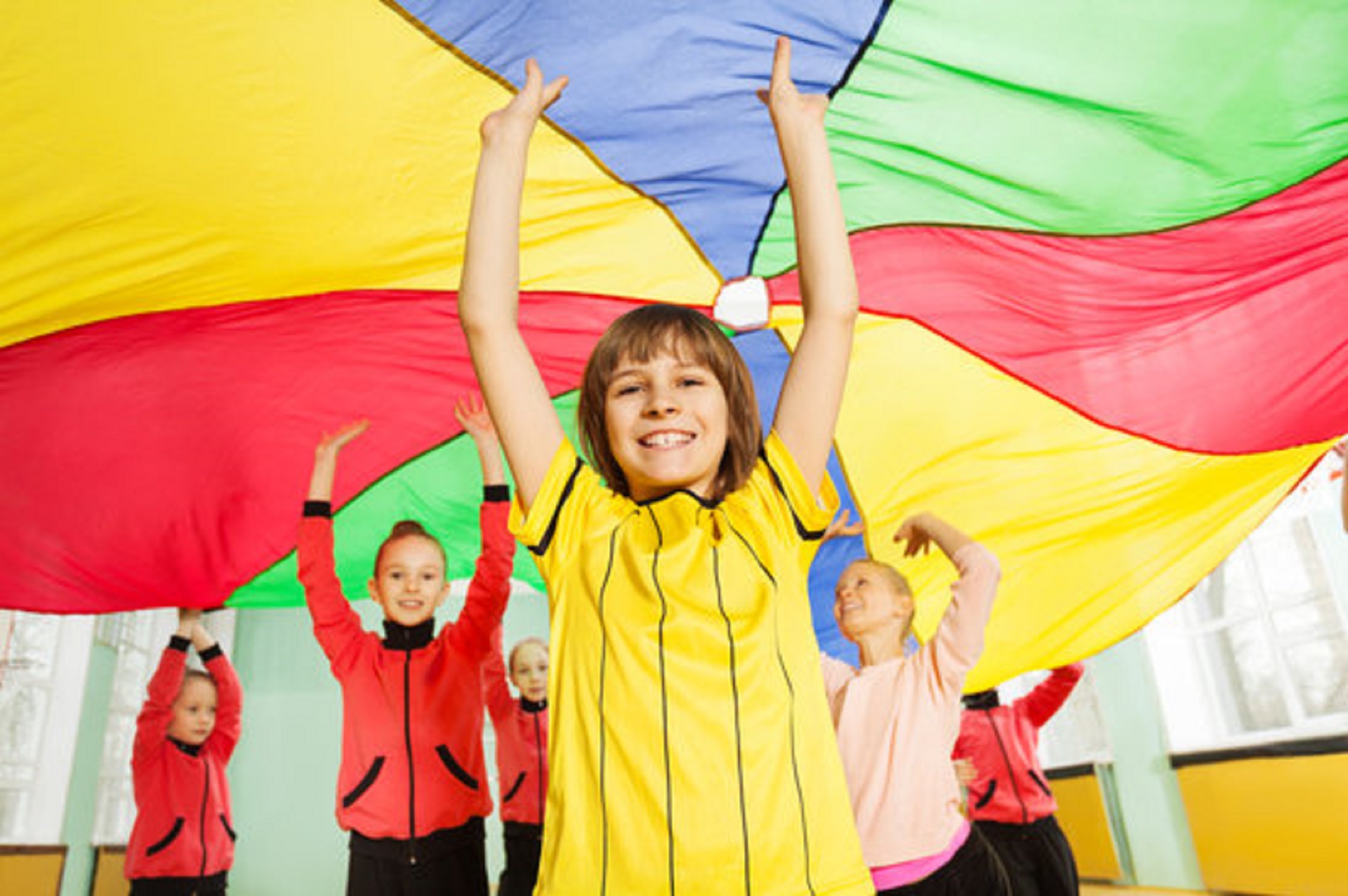 Smiling boys and girls playing parachute game